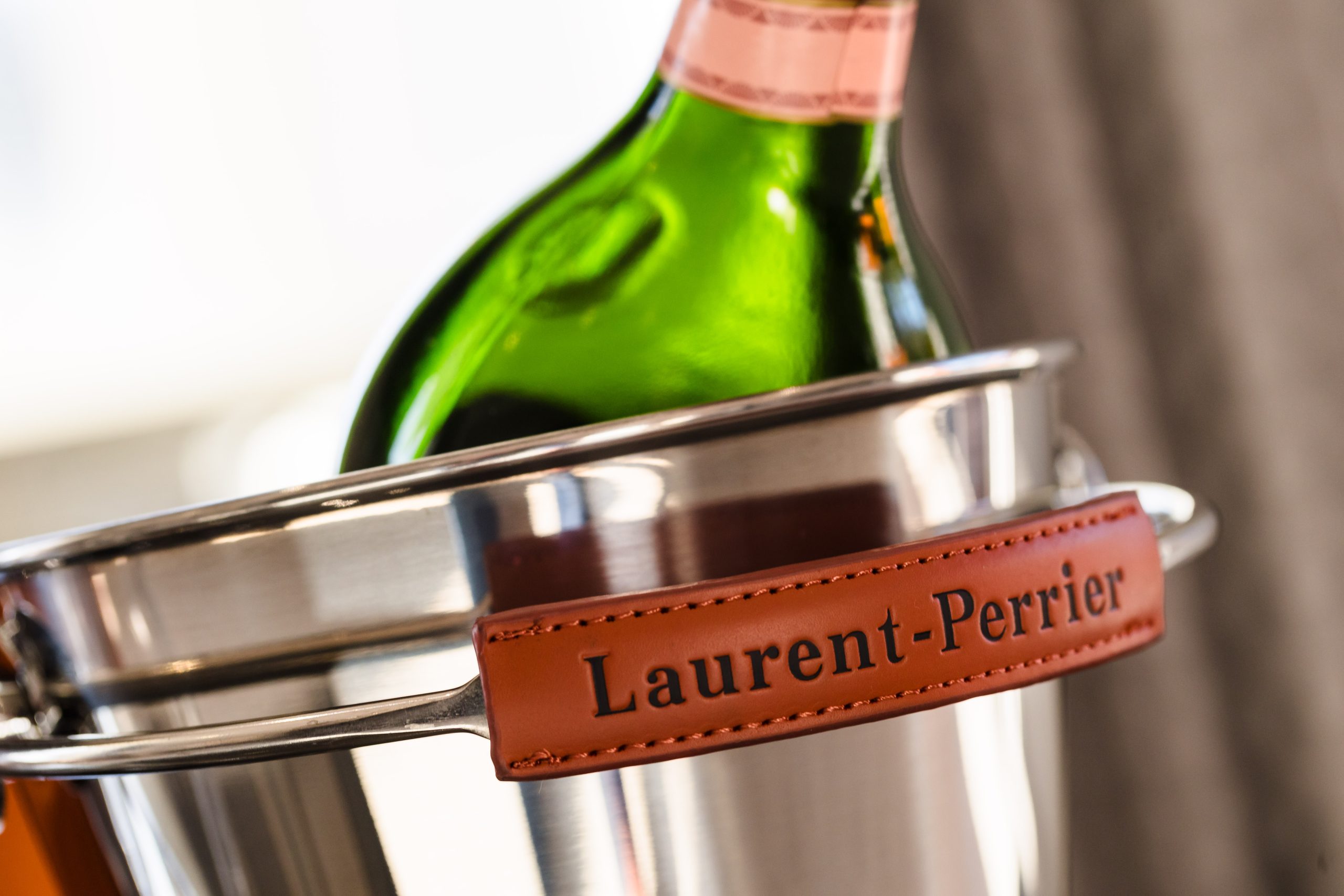 A green champagne bottle in a silver ice bucket with a brown label reading 