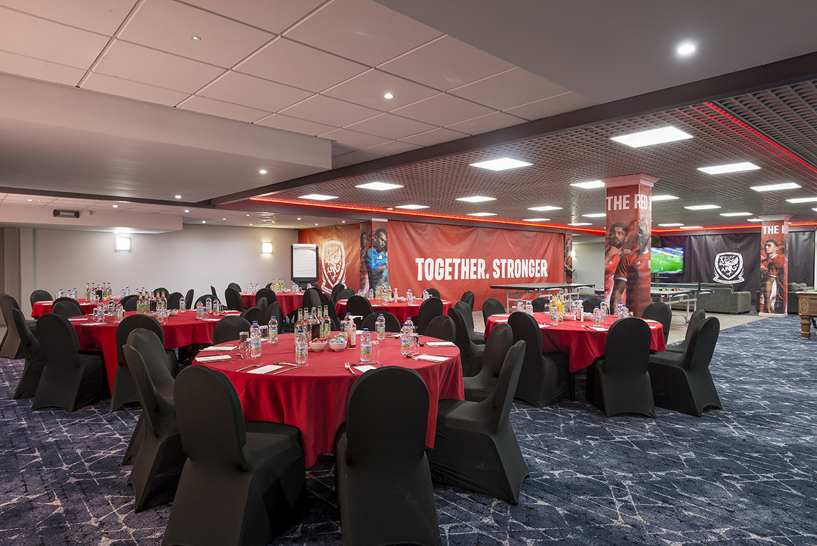 Banquet hall with round tables, red tablecloths, and black chairs. Banners with "Together. Stronger" phrase hang on the walls.