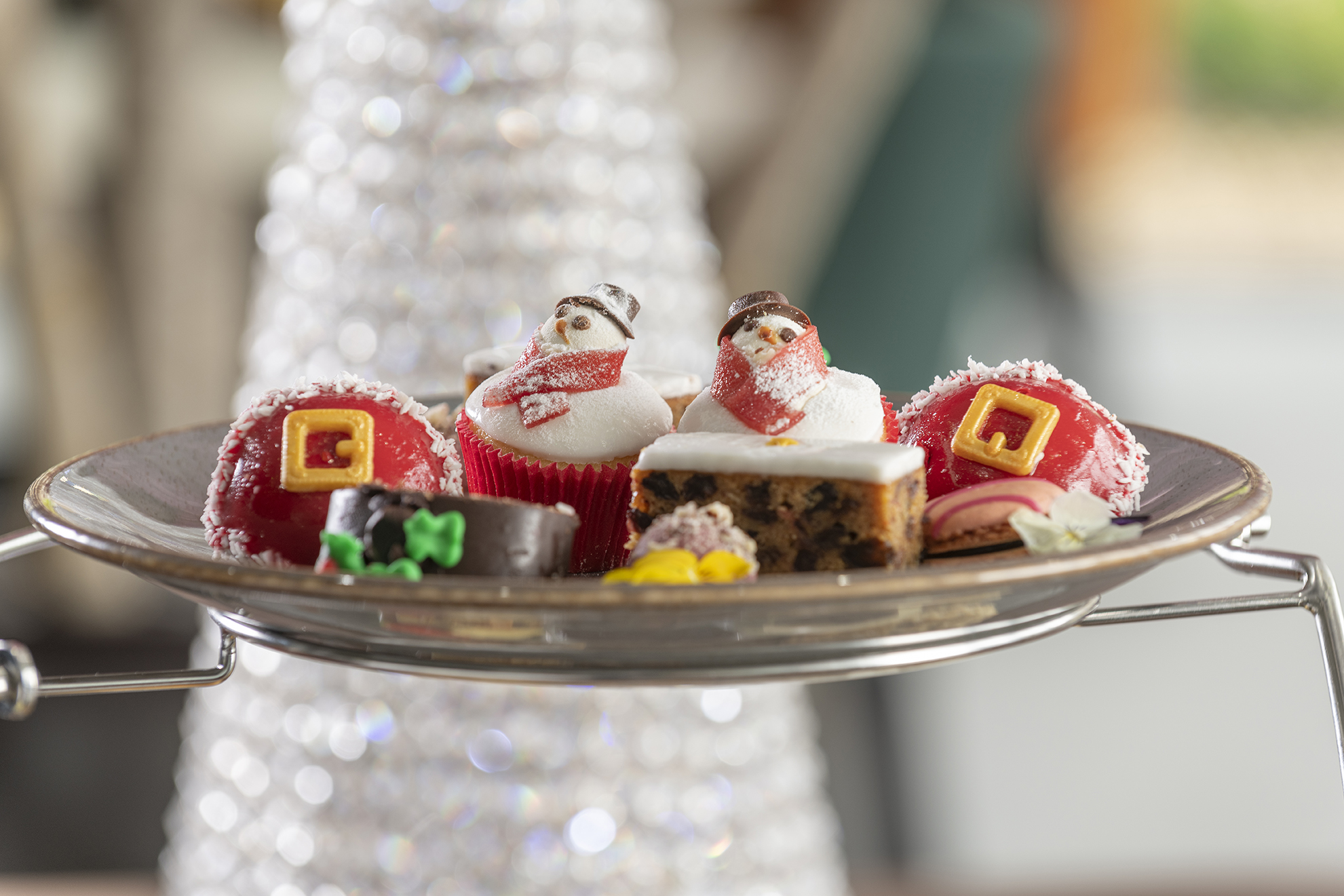 A plate of assorted festive holiday desserts, including snowman cupcakes, cake slices, and decorated pastries.