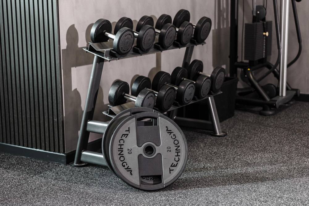 A rack of black dumbbells and Technogym 20 plates on the gym floor at a Hotel Gym South Wales.