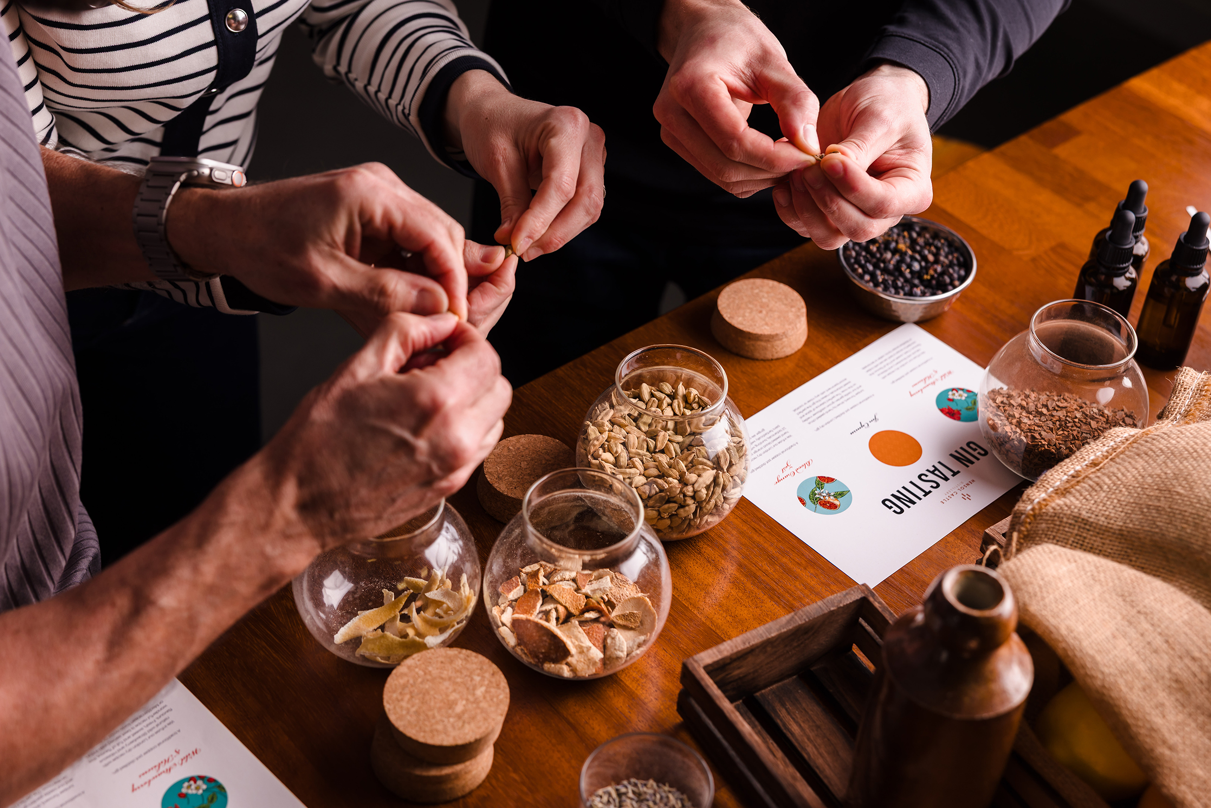 Three people prepare ingredients from glass jars on a table, planning meals and discussing hotel room bookings.